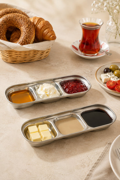 Kahvaltı sofrasında bal, kaymak, reçel, tereyağı ve tahin pekmezle dolu iki gümüş 3 bölmeli sunum kabı