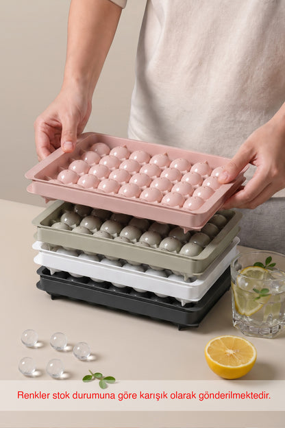 Üst üste istiflenmiş farklı renklerde kapaklı küre buz kalıpları ve limonlu içecek