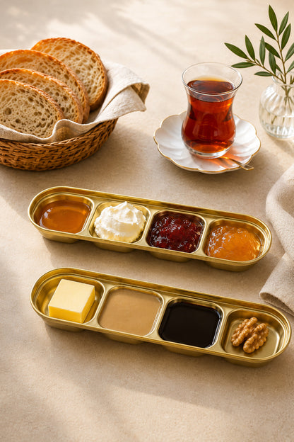 Kahvaltı sofrasında bal, kaymak, reçel ve tereyağı sunulan altın renkli bölmeli kaplar