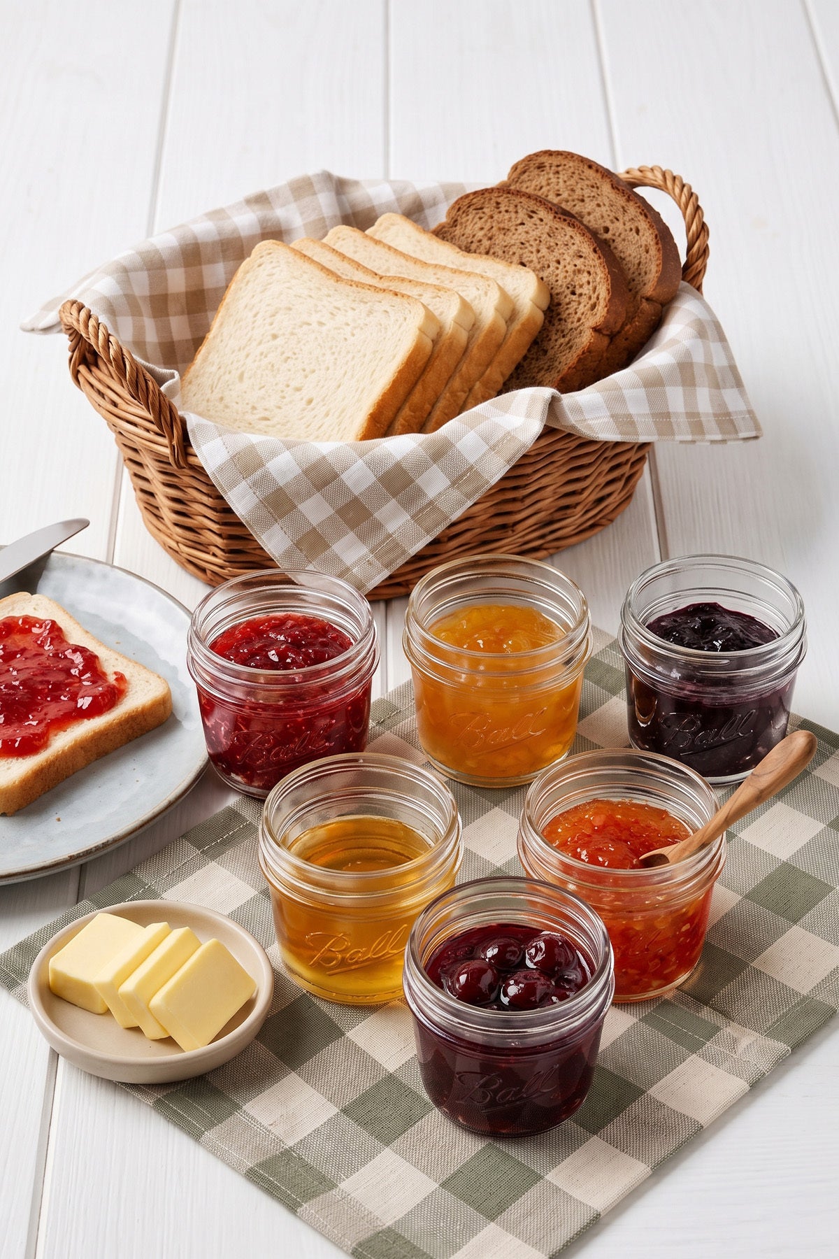 Ekmek sepeti ve tereyağı yanında reçel dolu cam mini kavanozlar kahvaltı sofrasında