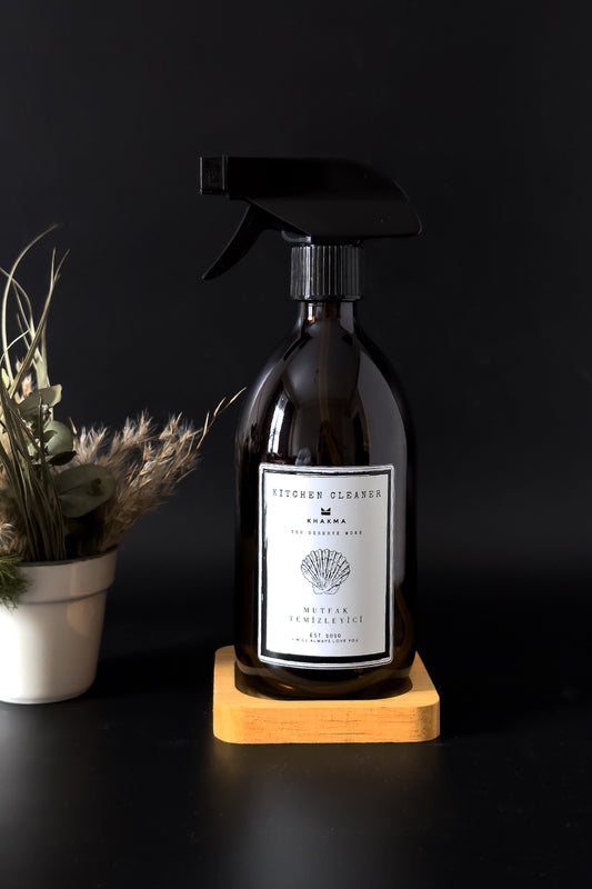 Kare ahşap stand üzerinde beyaz etiketli 500 ml amber cam sprey şişe, koyu zeminde