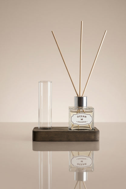 Ahşap stant üzerinde 50 ml Ocean difüzör şişesi, bambu çubuklar ve boş cam tüp vazo
