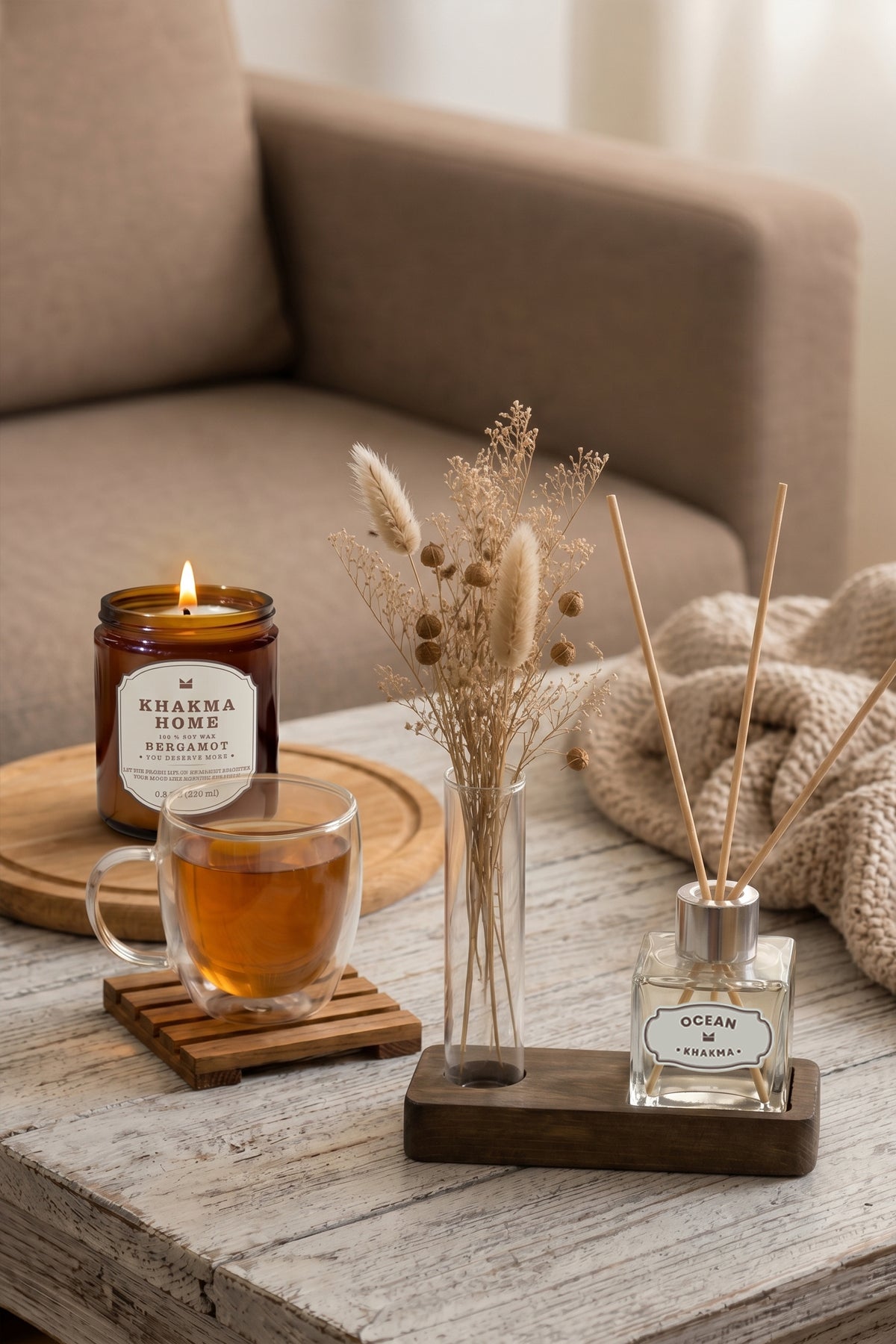 Sehpa üzerinde çay bardağı ve mumla birlikte ahşap standlı reed difüzör