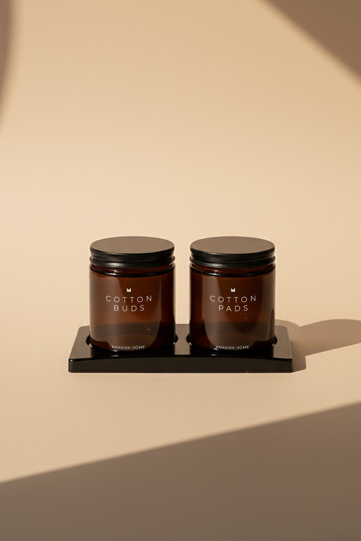 Siyah stand üzerinde Cotton Buds ve Cotton Pads yazılı iki amber cam kavanoz