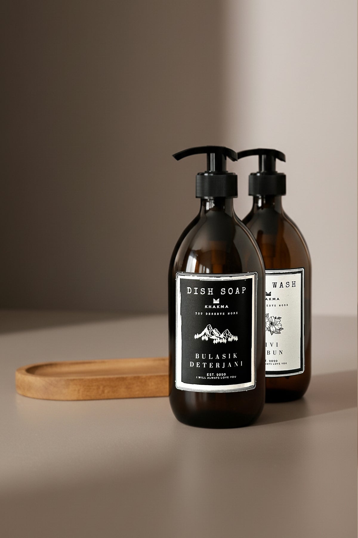 Siyah Bulaşık Deterjanı etiketli amber şişe önde, oval ahşap stand arkada