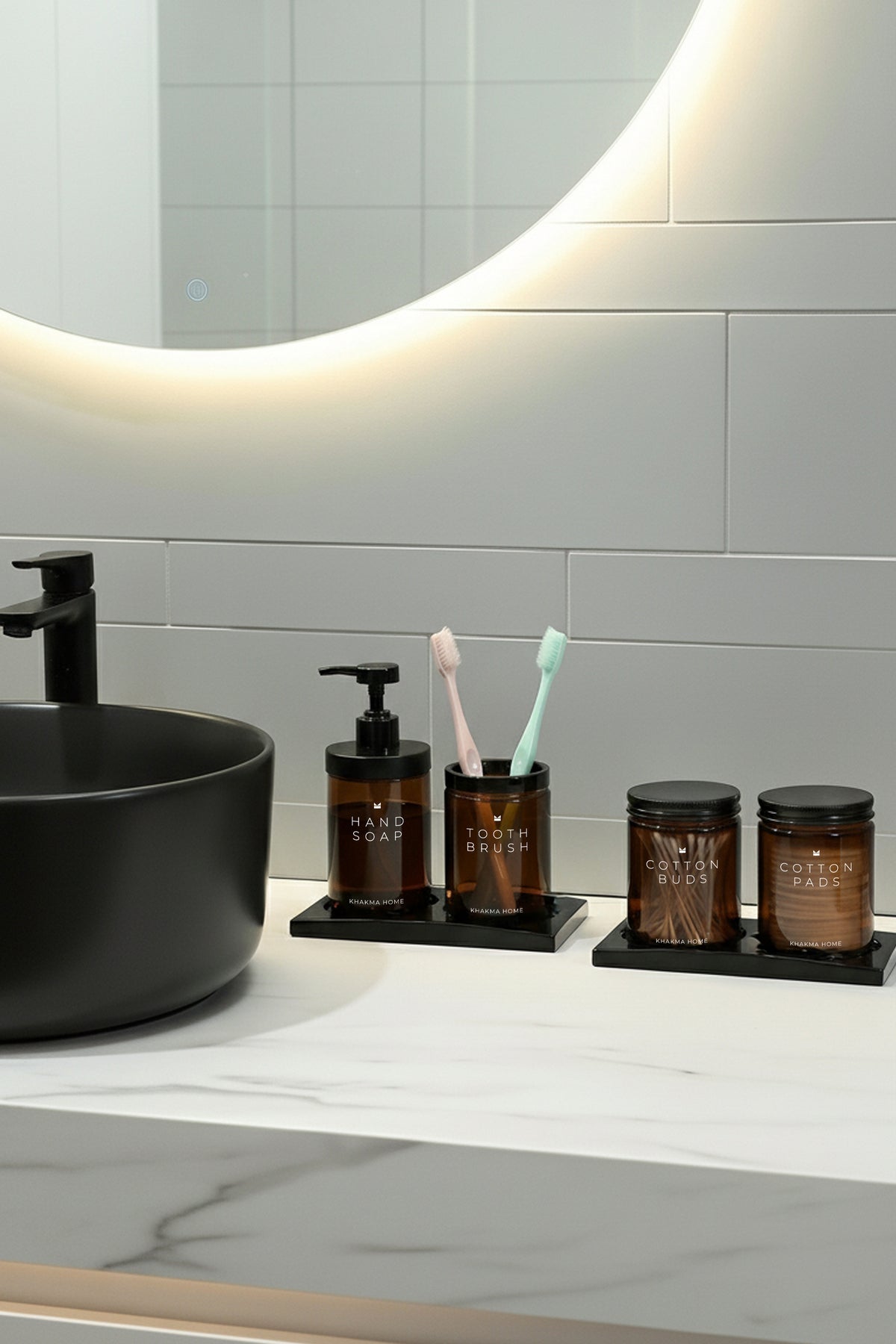 Işıklı ayna altında siyah lavabo yanında amber cam 4'lü banyo seti