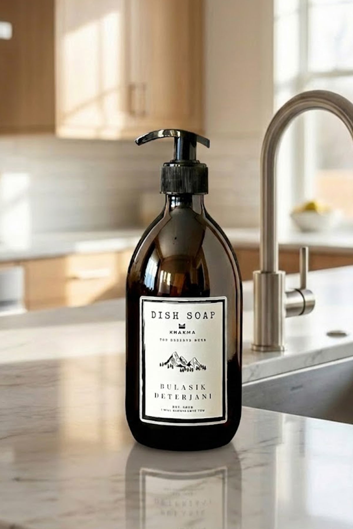 Mermer mutfak tezgâhında evye bataryası yanında amber cam deterjan şişesi