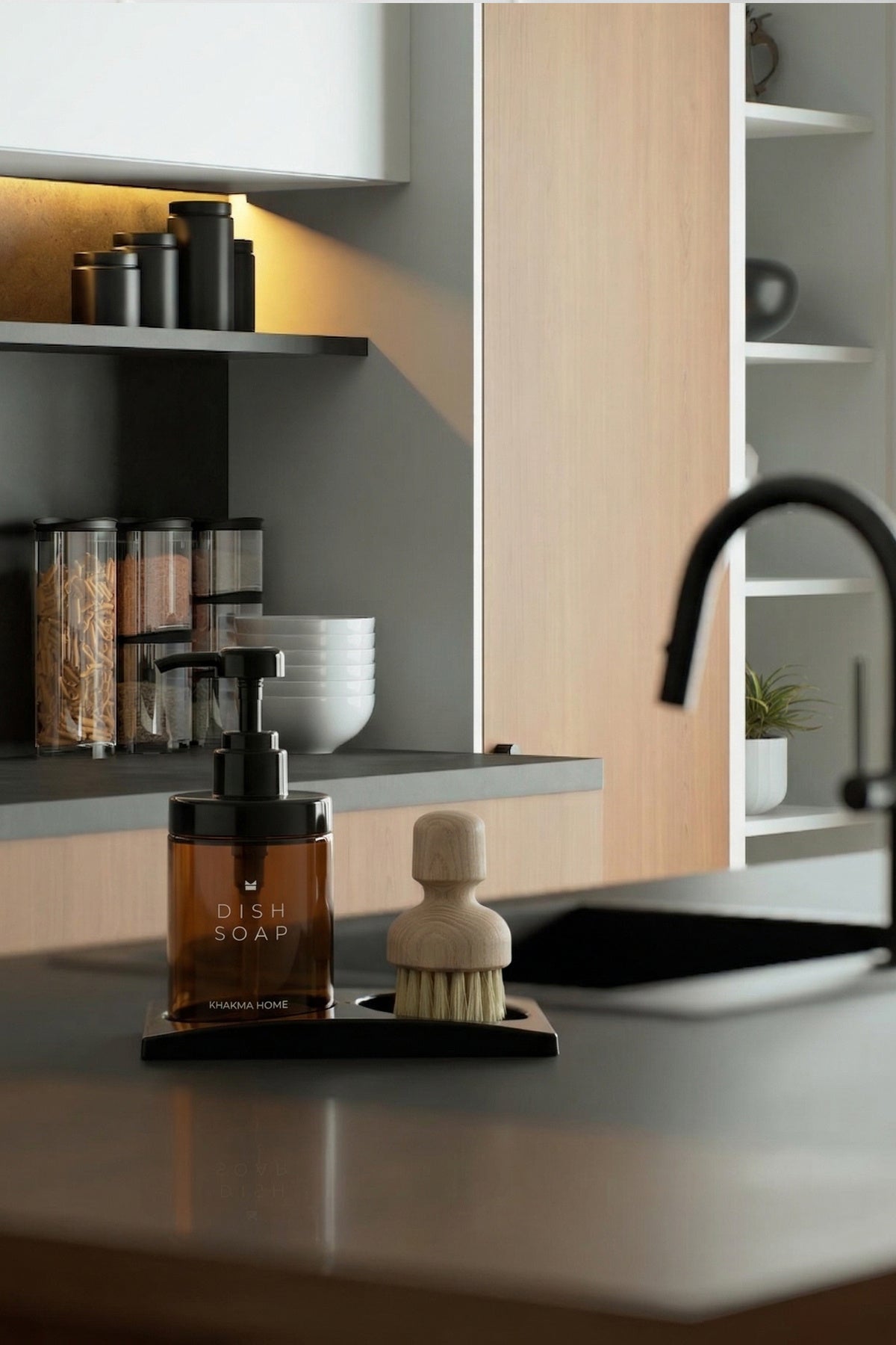 Koyu tonlu modern mutfakta evye kenarında standlı amber cam deterjanlık