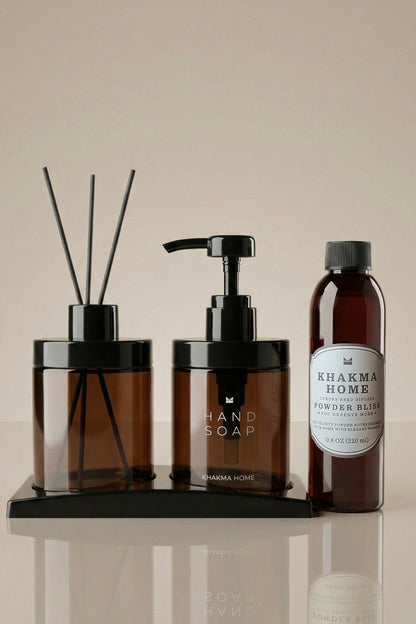 Siyah stand üzerinde amber cam difüzör ve Hand Soap sabunluk, yanında pudra kokulu yedek şişe
