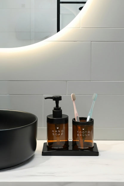 Siyah lavabo ve yuvarlak ayna önünde siyah standlı amber cam banyo seti