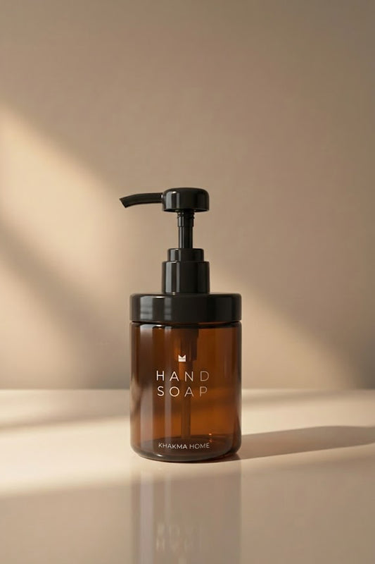 Beyaz tezgâhta Hand Soap yazılı amber cam sıvı sabunluk, siyah pompa