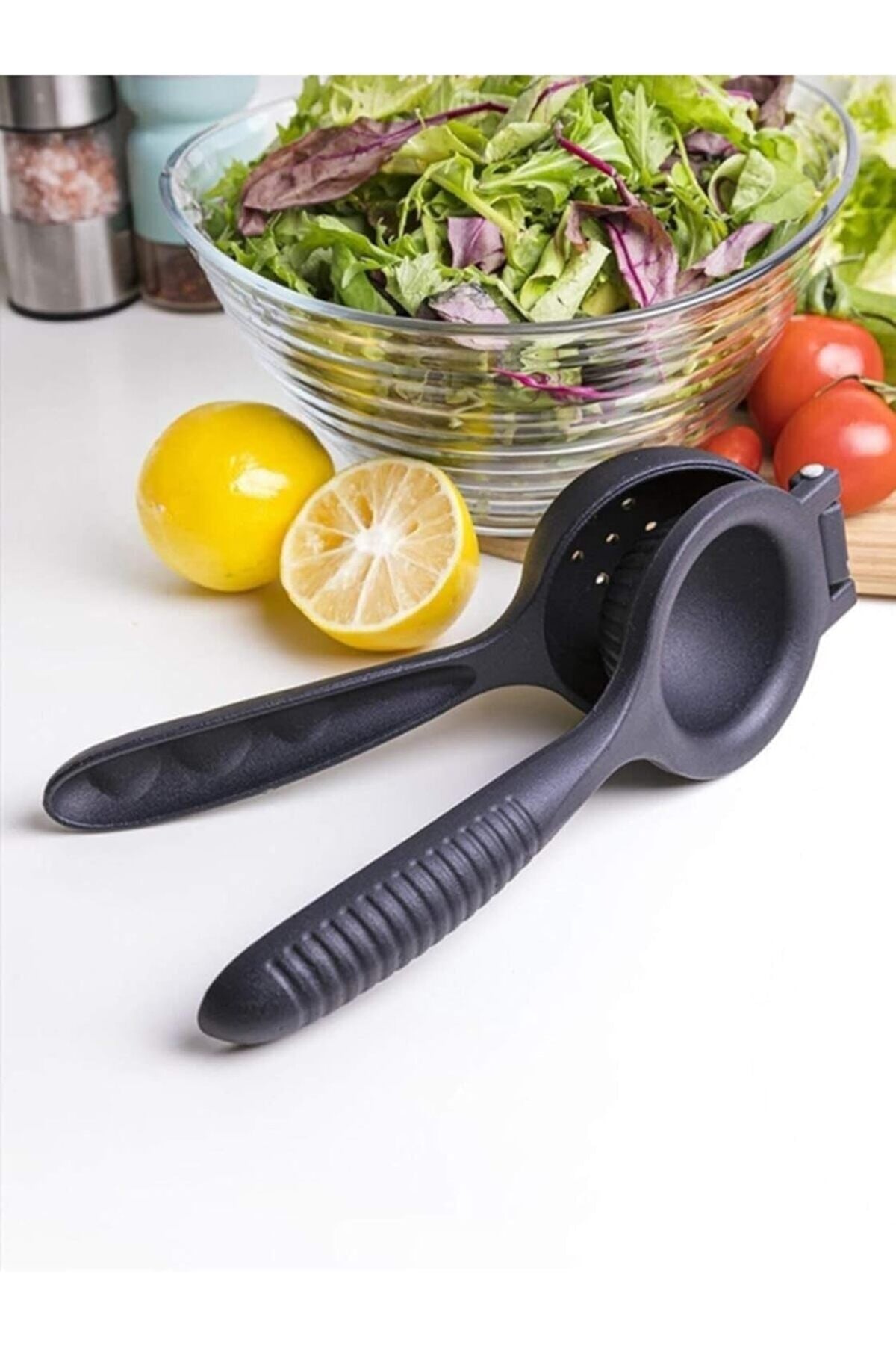 Salata kasesi, domates ve kesilmiş limonlar yanında siyah narenciye sıkacağı