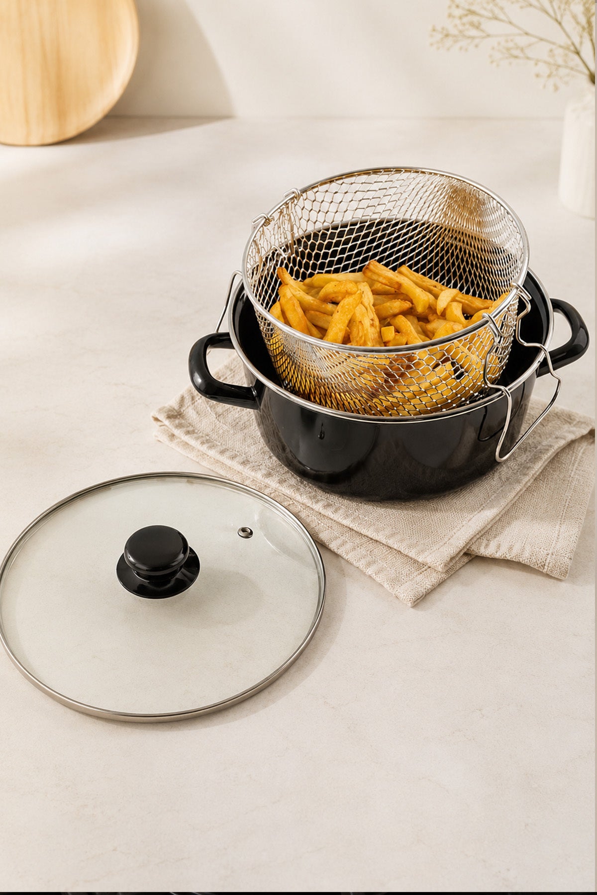 Patates kızartması dolu tel sepetiyle siyah emaye tencere ve cam kapak