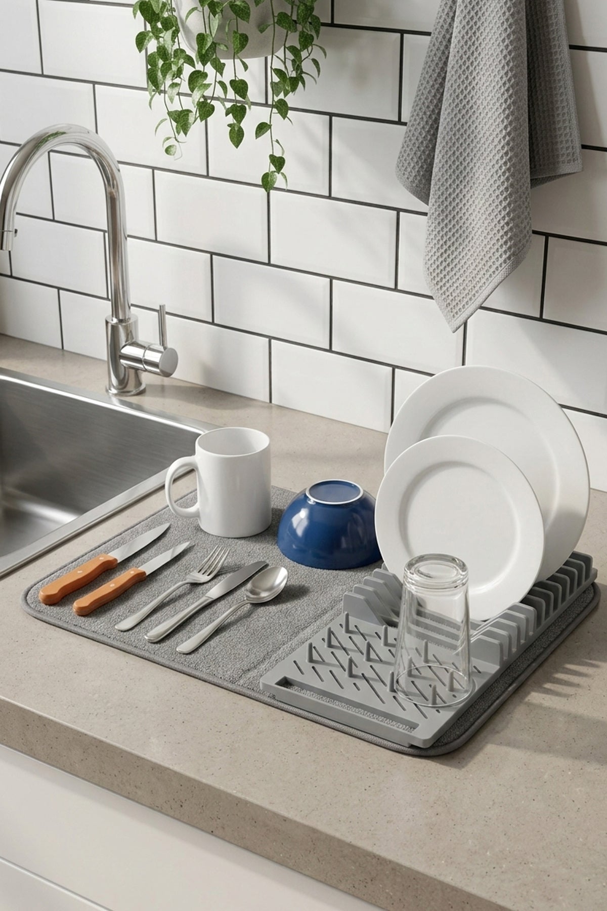 Lavabo yanındaki tezgâhta tabak ve bardaklarla bulaşık kurutma matı