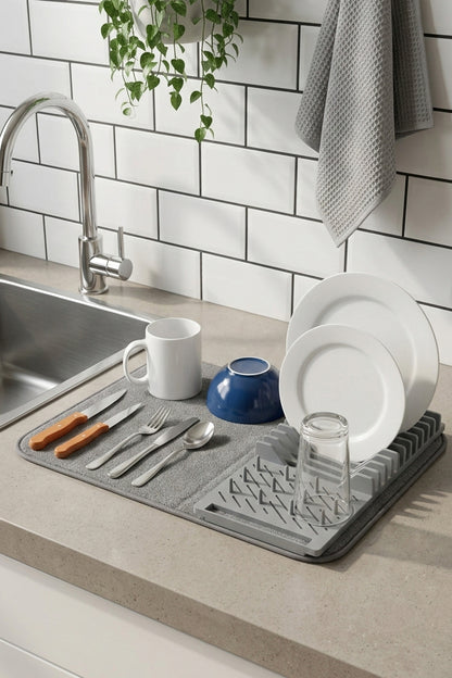 Lavabo yanındaki tezgâhta tabak ve bardaklarla bulaşık kurutma matı