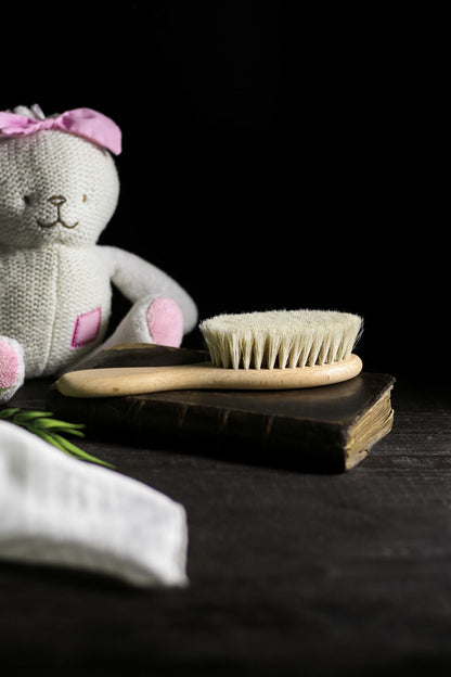 Pembe fiyonklu oyuncak ayı yanında doğal ahşap saplı yumuşak kıllı bebek fırçası