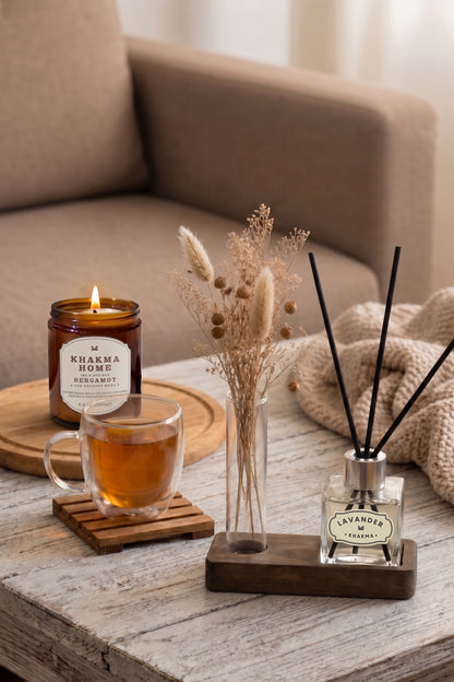 Sehpada mum, çay bardağı ve kuru çiçekler yanında ahşap standlı mini oda kokusu