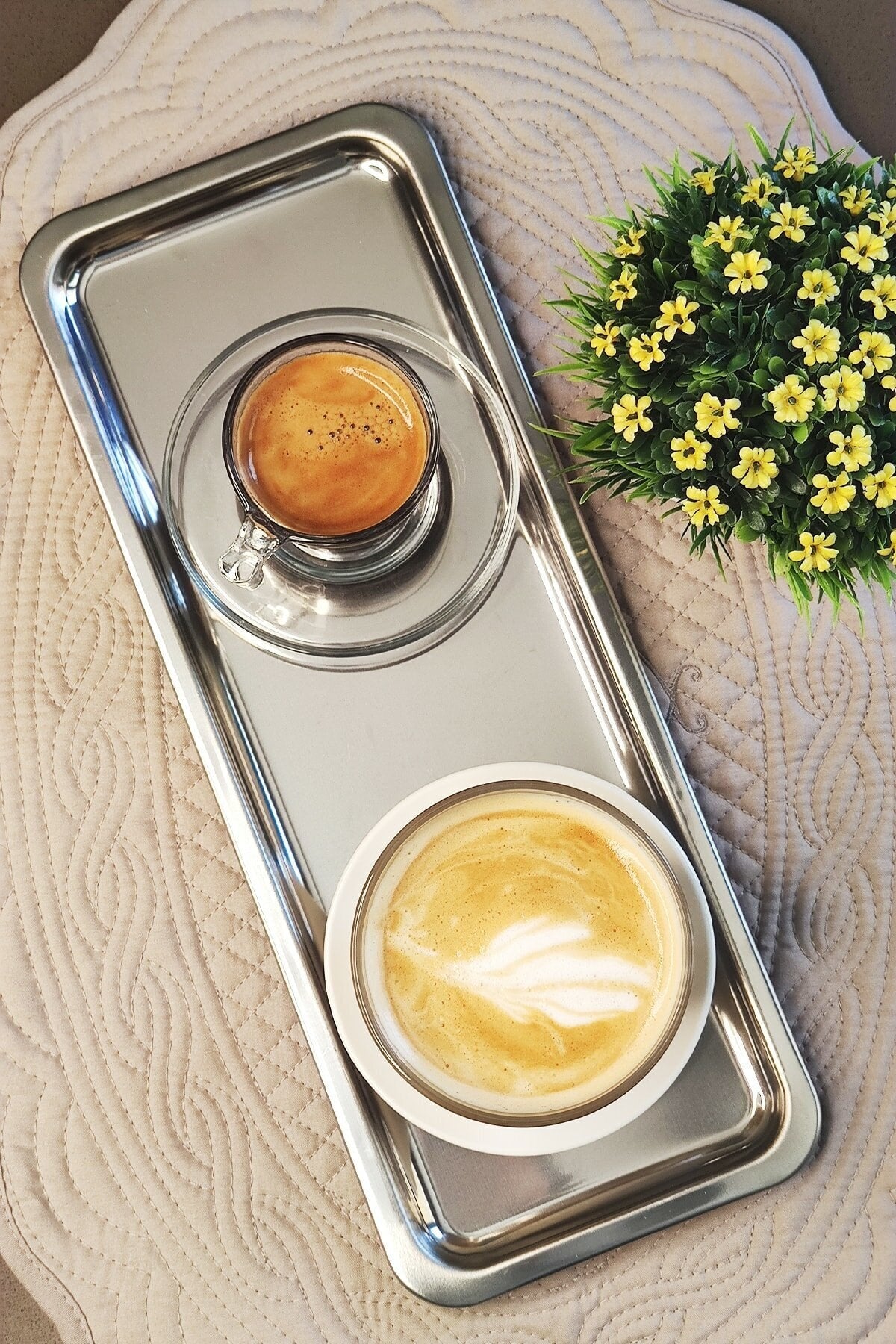 Paslanmaz çelik servis tepsisinde espresso ve latte fincanı, üstten görünüm