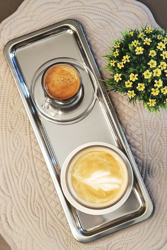 Paslanmaz çelik servis tepsisinde espresso ve latte fincanı, üstten görünüm