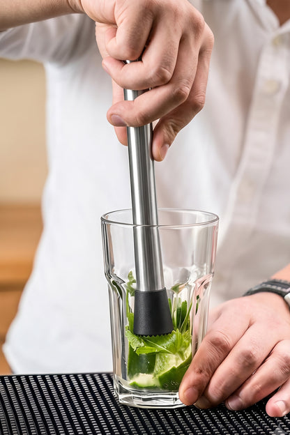 Barmen paslanmaz çelik muddler ile bardakta nane ve limonu ezerek mojito hazırlıyor
