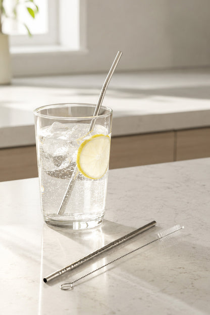 Limonlu buzlu su bardağında kıvrık çelik pipet, önünde düz pipet ve fırça