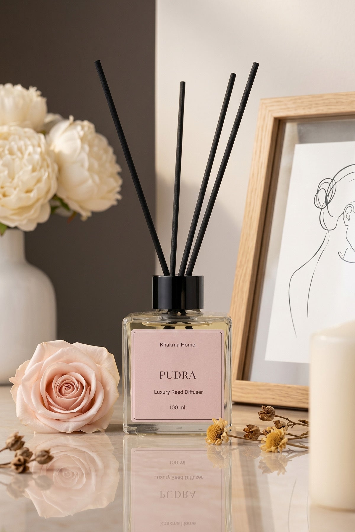 Pembe gül ve çerçeve yanında pudra etiketli çubuklu oda kokusu