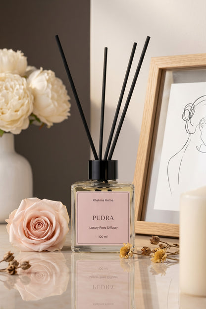 Pembe gül ve çerçeve yanında pudra etiketli çubuklu oda kokusu