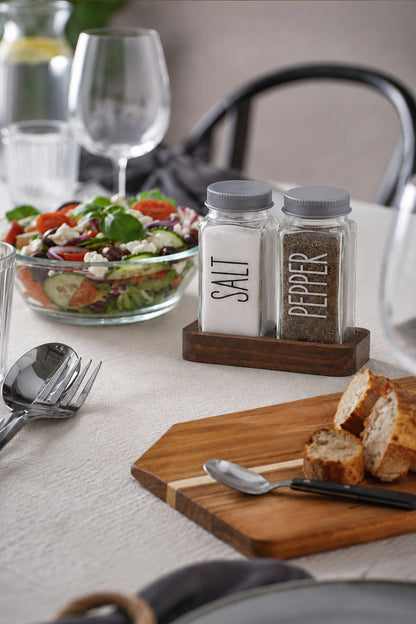 Salata ve ekmekle kurulmuş sofrada ahşap standlı tuzluk biberlik