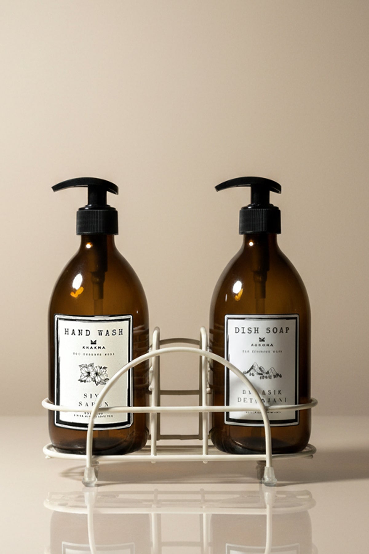 Beyaz metal stand içinde Hand Wash ve Dish Soap etiketli iki amber cam sabunluk
