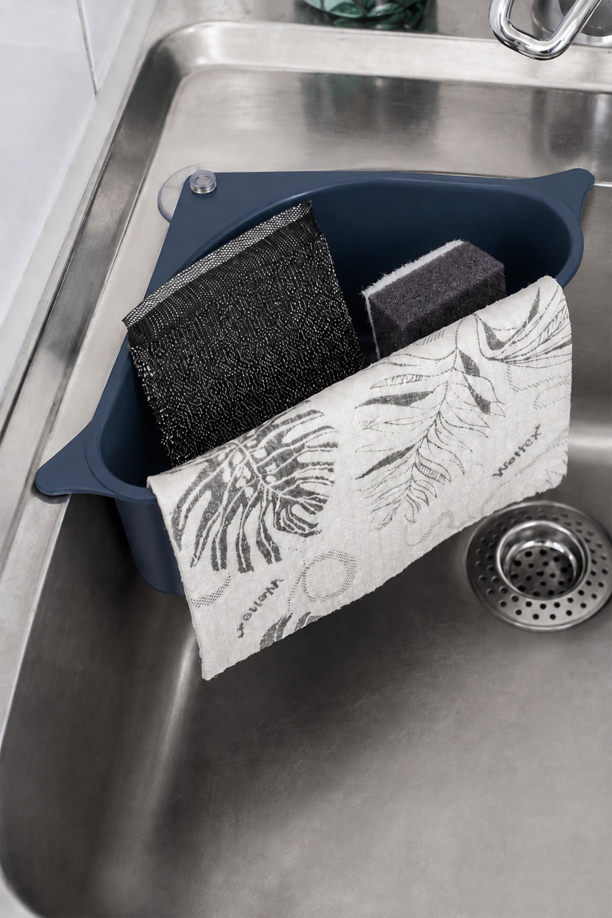 Lavabo köşe düzenleyici içinde bulaşık süngerleri ve desenli bulaşık bezi