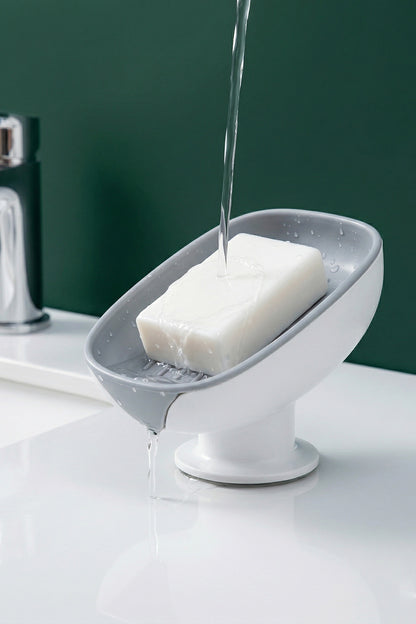 Lavabo kenarında katı sabunun suyu tahliye oluğundan akan vantuzlu sabunluk